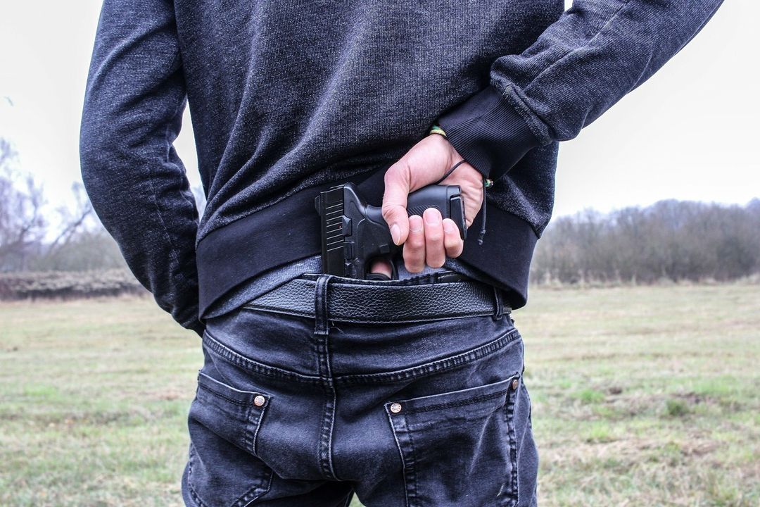 Symbolfoto eines Mannes mit einer Schusswaffe im Hosenbund.